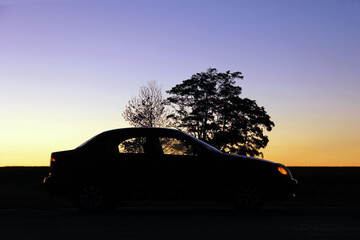Fototapeta na wymiar Car in the shade on the background of the sunset. Silhouette of the car. Wallpaper. Background