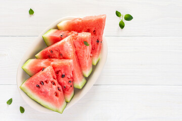 Juicy ripe sweet red watermelon slices with mint in a plate on a white background, top view