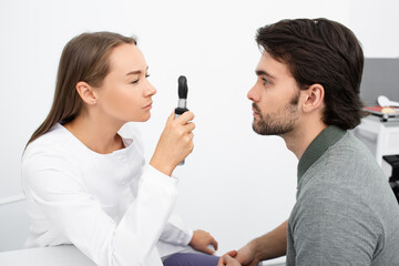 Woman optometrist examining a man's eyes with an ophthalmoscope. Eye exam of the adult people