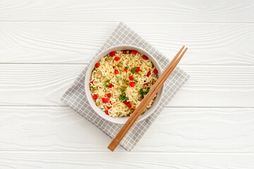 Instant noodle with pepper,peas and greens. White wooden background top view copy space