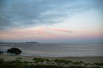 Obraz premium Photo of the beach in Galicia during sunrise. Beautiful pink and yellow clouds, empty beach. Amazing light during holidays.