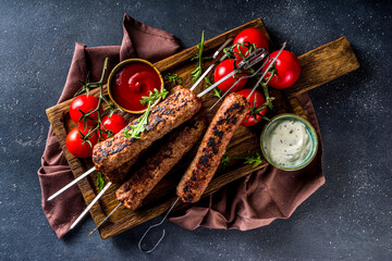 Shish kebab on skewers, from minced beef meat. Lula kebab, traditional Caucasian recipe. On black...