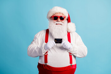 Portrait of his he nice attractive cheerful cheery white-haired Santa holding in hands using credit...