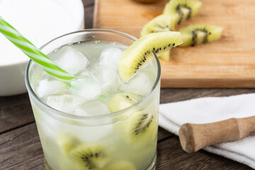 Brazilian kiwi caipirinha in a glass with ice with fruit slices over wooden board