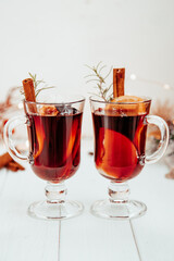  two glasses of hot mulled wine with rosemary on a white plate in a New Year's atmosphere