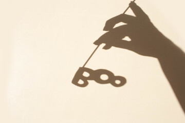 Hand holds decorative lettering boo on a white background. The trend of contrasting shadows for the holiday halloween