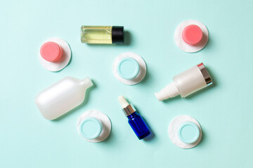 Obraz premium Group of small bottles for travelling on colored background. Copy space for your ideas. Flat lay composition of cosmetic products. Top view of cream containers with cotton pads