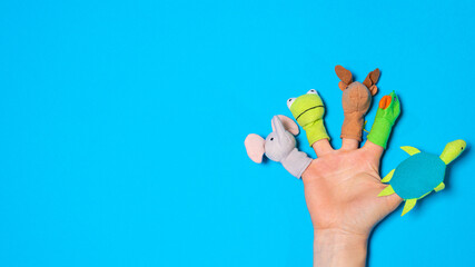 Fingers toys made of fabric on the hand on a blue background banner with a place for text. Fingers...