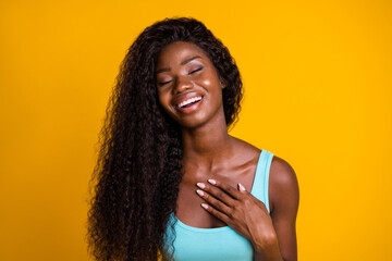 Photo portrait of young african american woman sighing in relief touching chest with hand isolated on vivid yellow colored background - obrazy, fototapety, plakaty