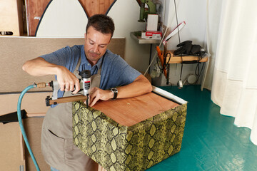 Qualified workman upholstering furniture in repair furniture