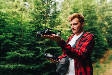 Young male professional launches drone in mountain forest to record video from bird's eye view. A young man launches a drone with his hands in the woods