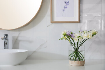 Beautiful freesia flowers on countertop in bathroom