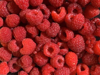 Background texture: red raspberries on a black background. Ripe raspberries, close-up.