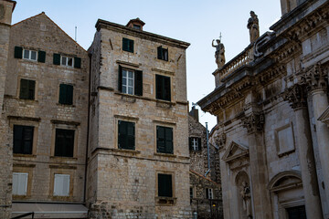 Esquina de fachada de iglesia con estatuas en la cornisa y edifico de piedra