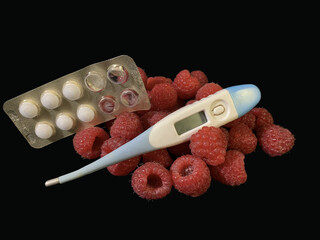 Red raspberries and medicines on a black background. Ripe raspberries for prevention and treatment. Concept: Disease prevention.