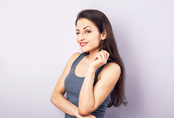 Fototapeta premium Funny grimacing brunette woman thinking and looking up in grey t-shirt with folded arms on purple background with empty copy space. Closeup