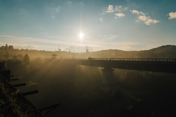 Railway bridge in the fog at sunrise. Silhouette of a bridge on the river on a background of sky and sun.