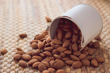 Closeup of brown fresh almonds seed in white cup on Water hyacinth placemats.