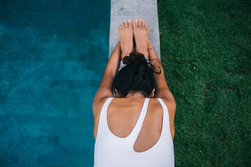 Flexible fit girl in sportswear stretching body during morning training at pool terrace, good...