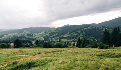 Fototapeta premium Landscape of the mountain village of Vorokhta, Carpathians from the meadow. Beautiful mountain village on a cloudy day. Travel to Ukraine