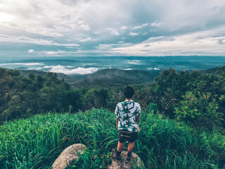 the man looking at the forest, mountain, and sky view at the viewpoint  at Doi Khun Tan National...