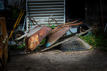 3 rusting wheel barrels sit outside the garage at a farm in Upstate NY