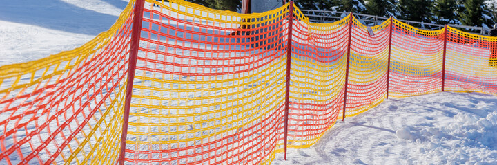 Colorful plastic fence on the ski slope in winter. Panoramic image