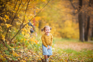 cute baby in autumn clothes look up. child in knitted jacket. girl looks at fall. walk outdoors