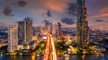 Aerial view of Taksin Bridge with Chao Phraya River, Bangkok Downtown, Thailand, Financial district and business center skylind and skyscaper urban city and high-rise buildings at night.