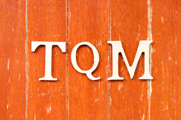 Alphabet letter in word TQM (Abbreviation of total quality management) on old red color wood plate background
