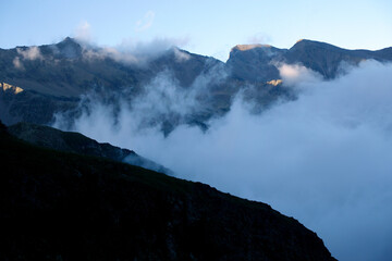 Clouds in a mountain valley. Sunset in the mountains.
Beautiful waves of clouds flowing in the mountains. The last rays of the sun on the tops of the mountains in the clouds at sunset. 