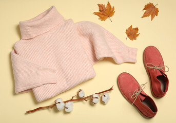 Flat lay composition with sweater and dry leaves on yellow background. Autumn season