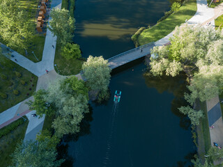 Aerial drone view. The catamaran sails under the bridge in the park.