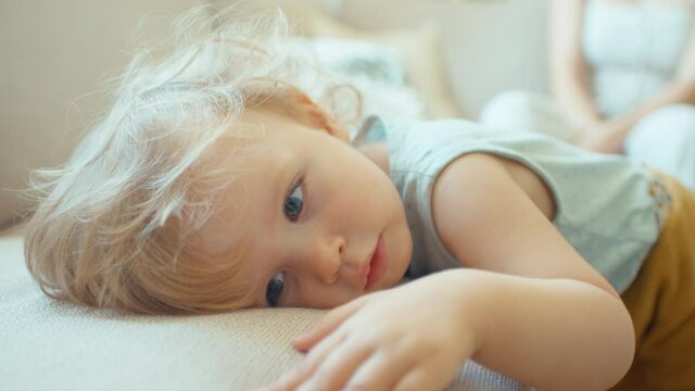 Portrait of young beautiful baby girl getting tired on a sofa.