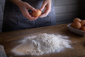 Breaking eggs by chefs hands during cooking dough for dumplings, pasta, bread, or pizza.  Cooking dumplings – step by step guide.