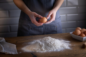 Breaking eggs by chefs hands during cooking dough for dumplings, pasta, bread, or pizza.  Cooking dumplings &ndash; step by step guide.
