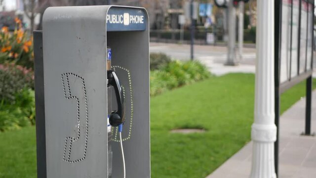 Retro coin-operated payphone station for emergency call on street, California USA. Public analog pay phone booth. Outdated technology for connection and telecommunication service. Cell handset on box.