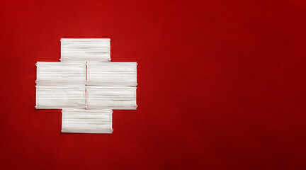 COVID-19 Warning sign, Red Cross made with white masks on red background. Red Cross flag. Red...