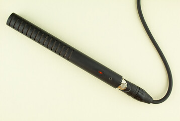 Professional instrumental condenser microphone with cable on beige background.