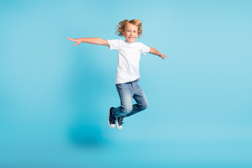 Obraz premium Photo of little kid jump look camera hands wear white shirt jeans sneakers isolated blue color background