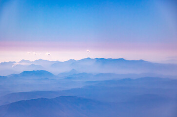 Fototapeta na wymiar Atmospheric and beautiful soft photos from the airplane window, mountains on the horizon and beautiful volumetric landscapes, pink tint