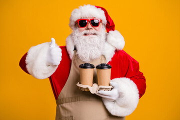 Close-up portrait of his he nice attractive cheerful fat overweight Santa waiter holding in hands two cups order latte showing thumbup isolated bright vivid shine vibrant yellow color background