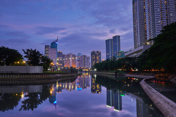Jakarta skyline reflected on water in the evening. Office building in Jakarta city with lights