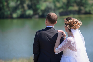 The bride and groom stand back, hold hands. 