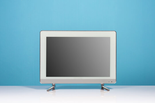 LCD television monitor on white table on blue wall background, flat screen tv