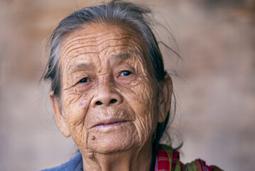 Portrait, Asian old or elderly woman sitting alone smiling, wrinkled skin, white hair, gray hair, looking at camera, 80 years old grandmother's face, close-up