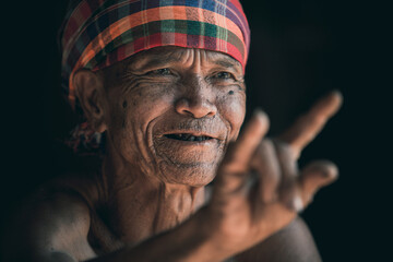 Portrait of Asian elderly man in the countryside, wrinkled skin on black background.