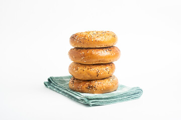 A Stack Of Four Freshly Baked Bagels On A Green Napkin