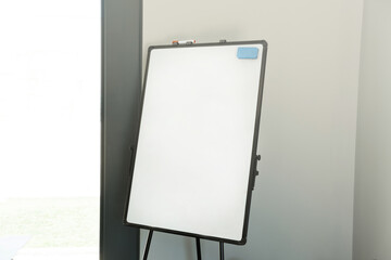 Photo of empty white board or flip chart with space for text in office