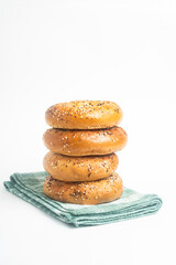 A Stack Of Four Freshly Baked Bagels On A Green Napkin
